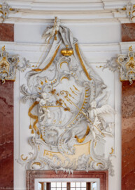 Schloss Bruchsal - Hauptbau - Beletage - Kuppelsaal - Stuckdraperie, oberhalb des Durchgangs zum Fürstensaal - Engel halten die bischöflichen Insignien der geistlichen und weltlichen Macht (ursprünglich geschaffen von Johann Michael Feichtmayr) (aufgenommen im Mai 2018, am späten Nachmittag)