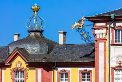 Schloss Bruchsal - Südlicher Verbindungsbau - Von Osten / Hofseite - Blick vom Balkon des Torwachtgebäudes auf die Dachspitze des Verbindungsbaus mit der goldenen Krone und auf die Südostseite des Hauptbaus mit dem Drachen (aufgenommen im Mai 2018, am Vormittag) Schloss Bruchsal - Südlicher Verbindungsbau - Von Osten / Hofseite - Blick vom Balkon des Torwachtgebäudes auf die Dachspitze des Verbindungsbaus mit der goldenen Krone und auf die Südostseite des Hauptbaus mit dem Drachen (aufgenommen im Mai 2018, am Vormittag)