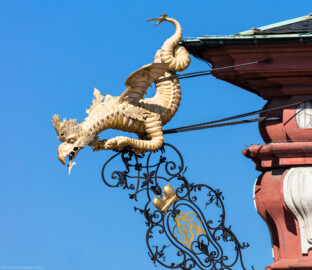 Schloss Bruchsal - Von Außen / Von Osten / Hofseite - Hauptbau - Oben, ganz links - Basilisk / Drache als Zierwasserspeier (aufgenommen im Mai 2018, am Vormittag) Schloss Bruchsal - Von Außen / Von Osten / Hofseite - Hauptbau - Oben, ganz links - Basilisk / Drache als Zierwasserspeier (aufgenommen im Mai 2018, am Vormittag)