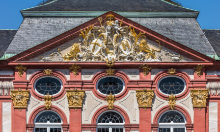 Schloss Bruchsal - Hauptbau - Von Außen / Von Osten / Hofseite - Blick vom Balkon des Torwachtgebäudes auf den oberen Teil des Mittelrisalits der Ostfassade und auf den Dreiecksgiebel mit dem Wappen (unten: Familienwappen des Kardinals Schönborn, links: Wappen des Hochstift Speyer, rechts: Wappen der Propstei Weißenburg) (aufgenommen im Mai 2018, um die Mittagszeit) Schloss Bruchsal - Hauptbau - Von Außen / Von Osten / Hofseite - Blick vom Balkon des Torwachtgebäudes auf den oberen Teil des Mittelrisalits der Ostfassade und auf den Dreiecksgiebel mit dem Wappen (unten: Familienwappen des Kardinals Schönborn, links: Wappen des Hochstift Speyer, rechts: Wappen der Propstei Weißenburg) (aufgenommen im Mai 2018, um die Mittagszeit)