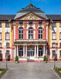 Schloss Bruchsal - Hauptbau - Von Außen / Von Osten / Hofseite - Blick vom Balkon des Torwachtgebäudes auf die Ostfassade mit dem Mittelrisalit, dem Balkon, dem Fürstensaal und dem Dreiecksgiebel (aufgenommen im Mai 2018, um die Mittagszeit) Schloss Bruchsal - Hauptbau - Von Außen / Von Osten / Hofseite - Blick vom Balkon des Torwachtgebäudes auf die Ostfassade mit dem Mittelrisalit, dem Balkon, dem Fürstensaal und dem Dreiecksgiebel (aufgenommen im Mai 2018, um die Mittagszeit)