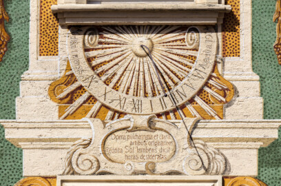 Schloss Bruchsal - Nördliche Orangerie / Nebendienstdienerbau - Von außen / Von Süden - Südfassade - Sonnenuhr;  Inschrift am Zahlenband: "Ad diem 1. mensis / Augusti a(nno) 1904" / "Am ersten Tag des Monats August im Jahre 1904"; Inschrift unterhalb er Sonnenuhr: "Opera pulcherrima et clara / artibus originalibus / Reddita Sol lambens dicit / horas desideratas" / "Während die Sonne auf die schönen und herrlichen Bauwerke, die mit originaler Kunst aufgeführt sind, ihre Strahlen wirft, zeigt sie ihre Stunden an", übersetzt von Bruno Schallbach (ursprünglich gemalt von Giovanni Francesco Marchini, zwischen 1732 und 1737, restauriert von Josef Mariano Kitschker, zwischen 1900 und 1910, erneut restauriert von Klaus Siller (Fassadenmalerei) und  Walter Maschke (Allegorien), 1976) (aufgenommen im Mai 2018, am späten Nachmittag)