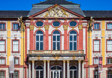 Schloss Bruchsal - Hauptbau - Von Außen / Von Osten / Hofseite - Blick vom Ehrenhof auf die Ostfassade mit dem Mittelrisalit, dem Fürstensaal und dem Balkon (aufgenommen im Juni 2018, am Vormittag) Schloss Bruchsal - Hauptbau - Von Außen / Von Osten / Hofseite - Blick vom Ehrenhof auf die Ostfassade mit dem Mittelrisalit, dem Fürstensaal und dem Balkon (aufgenommen im Juni 2018, am Vormittag)