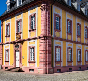 Schloss Bruchsal - Kirchenflügel - Von Nordosten / Hofseite - Blick von Nordosten auf den Kirchenflügel (mit dem Portal zu den ehemaligen Verwaltungsräumen und dem darüber liegenden Prunkwappen von Kardinal Graf Damian Hugo von Schönborn) (aufgenommen im Juni 2018, am späten Vormittag)