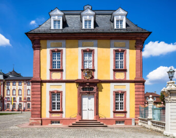 Schloss Bruchsal - Kammerflügel - Von Osten / Hofseite - Östliche Kopfseite des Kammerflügels (mit dem Portal und dem darüber liegenden Prunkwappen von Kardinal Graf Damian Hugo von Schönborn) (aufgenommen im Juli 2018, um die Mittagszeit)