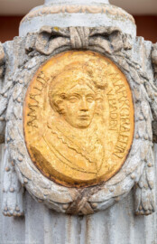 Schloss Bruchsal - Kanzleibau / Amalienbrunnen - Von Westen - Blick vom Vorplatz des Kanzleibaus auf das westliche Medaillon des Amalienbrunnens mit einem Bildnis von Amalie von Hessen-Darmstadt (Brunnen entworfen von Fritz Hirsch, aufgestellt 1912; Medaillon entworfen von Heinrich Ehehalt) (aufgenommen im Juli 2018, am späten Nachmittag) Schloss Bruchsal - Kanzleibau / Amalienbrunnen - Von Westen - Blick vom Vorplatz des Kanzleibaus auf das westliche Medaillon des Amalienbrunnens mit einem Bildnis von Amalie von Hessen-Darmstadt (Brunnen entworfen von Fritz Hirsch, aufgestellt 1912; Medaillon entworfen von Heinrich Ehehalt) (aufgenommen im Juli 2018, am späten Nachmittag)