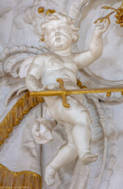 Schloss Bruchsal - Hauptbau - Beletage - Kuppelsaal - Stuckdraperie, oberhalb des Durchgangs zum Fürstensaal - Linker Engel mit bischöflichen Insignien der weltlichen Macht (ursprünglich geschaffen von Johann Michael Feichtmayr) (aufgenommen im Juli 2018, am  Nachmittag)