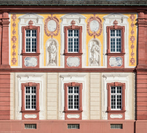 Schloss Bruchsal - Kirchenflügel / Hofkirche / St. Damian und Hugo - Von aussen - Von Westen - Blick vom Kavaliersbau auf die Westfassade der Hofkirche / des Kirchenflügels mit den Heiligenfiguren von St. Damian und St. Hugo (gemalt von Walter Maschke), fünf Landschaftgrisaillen und der illusionistischen Fassadenmalerei (ursprünglich gemalt von Giovanni Francesco Marchini, zwischen 1732 und 1737) (aufgenommen im August 2018, am späten Nachmittag) Schloss Bruchsal - Kirchenflügel / Hofkirche / St. Damian und Hugo - Von aussen - Von Westen - Blick vom Kavaliersbau auf die Westfassade der Hofkirche / des Kirchenflügels mit den Heiligenfiguren von St. Damian und St. Hugo (gemalt von Walter Maschke), fünf Landschaftgrisaillen und der illusionistischen Fassadenmalerei (ursprünglich gemalt von Giovanni Francesco Marchini, zwischen 1732 und 1737) (aufgenommen im August 2018, am späten Nachmittag)
