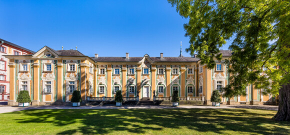 Schloss Bruchsal - Südliche Orangerie / Kavaliersbau - Von Außen - Von Westen - Blick auf die Westfassade der Orangerie (Fassade der Orangerie ursprünglich gemalt von Giovanni Francesco Marchini, zwischen 1732 und 1737, restauriert von Josef Mariano Kitschker, zwischen 1900 und 1910, erneut restauriert von Klaus Siller (Fassadenmalerei) und  Walter Maschke (Allegorien), 1976) (aufgenommen im September 2018, am  Nachmittag)