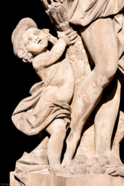 Schloss Bruchsal - Garten - Hauptachse, Nordseite, 1. Skulptur von Osten - Kindliche Figur links unten der Skulptur "Der Sommer" aus dem Skulpturenensemble "Vier Jahreszeiten" (Kopie; Original gehauen 1759 von Joachim Günther, befindet sich im Harvard Art Museum / Fogg Museum) (aufgenommen im September 2018, am späten Nachmittag)