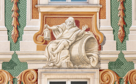 Schloss Bruchsal - Südliche Orangerie / Kavaliersbau - Von Außen - Nordseite - Von Norden - Blick auf die mittlere Allegorie bzw. Figur: "Diogenes" (antiker griechischer Philosoph, mit Laterne und Fass) (ursprünglich gemalt von Giovanni Francesco Marchini, zwischen 1732 und 1737, restauriert von Josef Mariano Kitschker, zwischen 1900 und 1910, erneut restauriert 1976 von Klaus Siller (Fassadenmalerei) und  Walter Maschke (Allegorien)) (aufgenommen im September 2018, am späten Vormittag)
