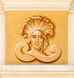 Schloss Bruchsal - Südliche Orangerie / Kavaliersbau - Von Außen - Nordseite, rechts/westlich, oben - Von Norden - Blick auf das rechte obere Kopfbild (ursprünglich gemalt von Giovanni Francesco Marchini, zwischen 1732 und 1737, restauriert von Josef Mariano Kitschker, zwischen 1900 und 1910, erneut restauriert 1976 von Klaus Siller (Fassadenmalerei) und  Walter Maschke (Allegorien)) (aufgenommen im September 2018, um die Mittagszeit)