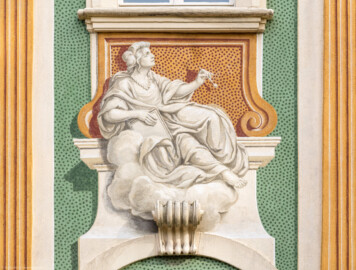 Schloss Bruchsal - Südliche Orangerie / Kavaliersbau - Von Außen - Von Westen - Blick auf die 7. (von Norden/von links gezählt) Allegorie bzw. Figur: vermutlich die "Bildhauerei" (ursprünglich gemalt von Giovanni Francesco Marchini, zwischen 1732 und 1737, restauriert von Josef Mariano Kitschker, zwischen 1900 und 1910, erneut restauriert von Klaus Siller (Fassadenmalerei) und  Walter Maschke (Allegorien), 1976) (aufgenommen im September 2018, am späten Nachmittag)