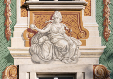 Schloss Bruchsal - Südliche Orangerie / Kavaliersbau - Von Außen - Von Westen - Blick auf die 13. (von Norden/von links gezählt) Allegorie bzw. Figur: vermutlich "Gefährtin der Diana" (Göttin der Jagd) (ursprünglich gemalt von Giovanni Francesco Marchini, zwischen 1732 und 1737, restauriert von Josef Mariano Kitschker, zwischen 1900 und 1910, erneut restauriert von Klaus Siller (Fassadenmalerei) und  Walter Maschke (Allegorien), 1976) (aufgenommen im September 2018, am späten Nachmittag)