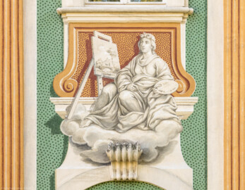 Schloss Bruchsal - Südliche Orangerie / Kavaliersbau - Von Außen - Von Westen - Blick auf die 9. (von Norden/von links gezählt) Allegorie bzw. Figur: vermutlich die "Malerei" (ursprünglich gemalt von Giovanni Francesco Marchini, zwischen 1732 und 1737, restauriert von Josef Mariano Kitschker, zwischen 1900 und 1910, erneut restauriert von Klaus Siller (Fassadenmalerei) und  Walter Maschke (Allegorien), 1976) (aufgenommen im Oktober 2018, um die Mittagszeit)
