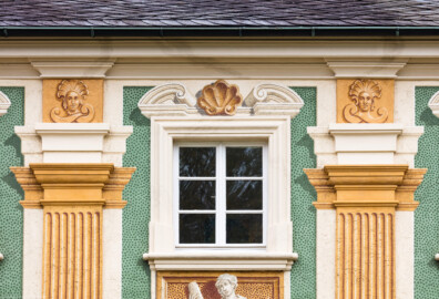Schloss Bruchsal - Nördliche Orangerie / Nebendienstdienerbau - Von Außen / Von Westen - Blick nach oben auf einen Ausschnitt der Westfassade mit der Illusionsmalerei (ursprünglich gemalt von Giovanni Francesco Marchini, zwischen 1732 und 1737, restauriert von Josef Mariano Kitschker, zwischen 1900 und 1910, erneut restauriert von Klaus Siller (Fassadenmalerei) und  Walter Maschke (Allegorien), 1976) (aufgenommen im Oktober 2018, am Nachmittag)
