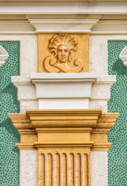 Schloss Bruchsal - Nördliche Orangerie / Nebendienstdienerbau - Von Außen / Von Westen - Blick auf ein Pilasterkapitell mit einer Kopfverzierung (ursprünglich gemalt von Giovanni Francesco Marchini, zwischen 1732 und 1737, restauriert von Josef Mariano Kitschker, zwischen 1900 und 1910, erneut restauriert von Klaus Siller (Fassadenmalerei) und  Walter Maschke (Allegorien), 1976) (aufgenommen im Oktober 2018, am Nachmittag)