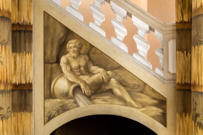 Schloss Bruchsal - Hauptbau - Erdgeschoss - Grotte, Nordostseite - Von Südwesten - Blick auf den nördlichen Treppenzwickel mit einem Flussgott (Malereien ursprünglich von Giovanni Francesco Marchini, 1731 bis 1736, rekonstruiert von Manfred Leitenmeier, 1971 bis 1980) (aufgenommen im Januar 2019, am Nachmittag)