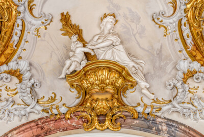 Schloss Bruchsal - Hauptbau / Corps de Logis - Beletage - Marmorsaal / Kaisersaal - Oberhalb des Durchgangs zum Kuppelsaal - Blick auf eine weibliche Figur und eine Putte sowie umgebende Rokoko-Stuckaturen (Stuckaturen ursprünglich von Johann Michael Feichtmayr) (aufgenommen im Februar 2019, am Nachmittag)