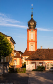 Schloss Bruchsal - Kirchturm - Von Außen / Von Westen - Blick auf den  Kirchturm der Hofkirche am Abend, die südliche Orangerie (links), den westlichen Bandhof (rechts) sowie die Hofapotheke (links der Mitte) (aufgenommen im April 2019, am frühen Abend)