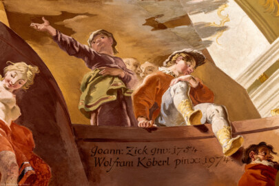 Schloss Bruchsal - Hauptbau / Corps de Logis - Beletage - Marmorsaal / Kaisersaal - Deckenfresko, äußere Zone, südlicher Teil der Ostseite - Unten: Hinweis auf den originalen Maler des Freskos, Johannes Zick, und die Jahresangabe der Fertiggstellung des originalen Gemäldes; darunter die Signatur von Wolfram Köberl mit der Jahresangabe der Fertiggstellung der originalgetreuen Rekonstruktion; links: Darstellung der Glücksgöttin Fortuna; oben rechts (Junge mit aufgestelltem Bein): Darstellung von Januarius Zick, Sohn von Johannes Zick, der am Fresko mitgearbeitet hat; oben links (Mädchen mit ausgestreckter Hand): Darstellung einer Schwester von Januarius Zick (Deckenfresko urspünglich gemalt 1754 von Johannes Zick, originalgetreu rekonstruiert 1971 bis 1974 von Wolfram Köberl; Stuck urspünglich von Johann Michael Feuchtmayer dem Jüngeren, rekonstruiert 1962 bis 1969 von Jakob und Josef Schnitzer) (aufgenommen im Mai 2019, am späten Nachmittag) Schloss Bruchsal - Hauptbau / Corps de Logis - Beletage - Marmorsaal / Kaisersaal - Deckenfresko, äußere Zone, südlicher Teil der Ostseite - Unten: Hinweis auf den originalen Maler des Freskos, Johannes Zick, und die Jahresangabe der Fertiggstellung des originalen Gemäldes; darunter die Signatur von Wolfram Köberl mit der Jahresangabe der Fertiggstellung der originalgetreuen Rekonstruktion; links: Darstellung der Glücksgöttin Fortuna; oben rechts (Junge mit aufgestelltem Bein): Darstellung von Januarius Zick, Sohn von Johannes Zick, der am Fresko mitgearbeitet hat; oben links (Mädchen mit ausgestreckter Hand): Darstellung einer Schwester von Januarius Zick (Deckenfresko urspünglich gemalt 1754 von Johannes Zick, originalgetreu rekonstruiert 1971 bis 1974 von Wolfram Köberl; Stuck urspünglich von Johann Michael Feuchtmayer dem Jüngeren, rekonstruiert 1962 bis 1969 von Jakob und Josef Schnitzer) (aufgenommen im Mai 2019, am späten Nachmittag)