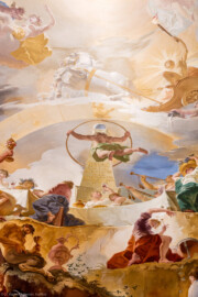 Schloss Bruchsal - Hauptbau / Corps de Logis - Beletage - Marmorsaal / Kaisersaal - Deckenfresko, Innere Zone, nordwestlich des Zentrums - Von Norden - Im Zentrum: der Weltbaumeister Demogorgon mit Schlangenring als Symbol der Ewigkeit, vor einem Obelisk mit einer Weltkugel oben; darüber: die speyerische "Gnadenjungfrau" Astraia im Tierkreis; oben: der Sonnengott Apoll mit seinem Sonnenwagen über dem  Zodiacus (dem Tierkreis); unten: das ewige Göttermahl (mit Posaunenbläsern) im Olymp als Symbol für das ewige Bestehen des Bistum Speyer; ganz unten links: ein zechender Satyr; ganz unten rechts: ein Paukenspieler - Inschrift auf dem Obelisk: "SPIRA HAEC PERPETUO SINE FINE REVOLUITUR ORBE. FELIX SPIRA CUI PRODROMA SPIRA STATUS." / Übersetzung von Barbara Strieder: "Diese Schlangenwindung wird in ewigem Kreislauf ohne Ende in sich selbst zurückgeführt, glückliches Speyer, dessen Wohlstand die im Sinnbild der Schlange gefasste Beständigkeit besitzt"  (Deckenfresko urspünglich gemalt 1754 von Johannes Zick, originalgetreu rekonstruiert 1971 bis 1974 von Wolfram Köberl; Stuck urspünglich von Johann Michael Feuchtmayer dem Jüngeren, rekonstruiert 1962 bis 1969 von Jakob und Josef Schnitzer) (aufgenommen im Januar 2020, am Nachmittag)
