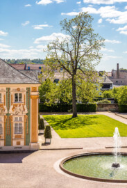 Schloss Bruchsal - Schlossterrasse, Südseite - Blick von oben vom westlichen Balkon auf die südliche Terrasse, links die südliche Orangerie / der Kavaliersbau (aufgenommen im Mai 2019, am Nachmittag)