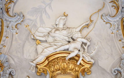Schloss Bruchsal - Hauptbau / Corps de Logis - Beletage - Marmorsaal / Kaisersaal - Oberhalb der Tür zum Balkon - Von Osten - Blick vom Durchgang zum Kuppelsaal nach Westen auf eine weibliche Figur und eine Putte (Stuckaturen ursprünglich von Johann Michael Feichtmayr) (aufgenommen im Mai 2019, am Nachmittag) Schloss Bruchsal - Hauptbau / Corps de Logis - Beletage - Marmorsaal / Kaisersaal - Oberhalb der Tür zum Balkon - Von Osten - Blick vom Durchgang zum Kuppelsaal nach Westen auf eine weibliche Figur und eine Putte (Stuckaturen ursprünglich von Johann Michael Feichtmayr) (aufgenommen im Mai 2019, am Nachmittag)