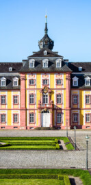 Schloss Bruchsal - Kirchenflügel / Hofkirche / St. Damian und Hugo - Von Norden / Hofseite - Blick vom Balkon des Kammerflügels / des Kammermusiksaals auf den Ehrenhof und den Mittelrisalit des Kirchenflügels (aufgenommen im Juni 2019, am Vormittag)