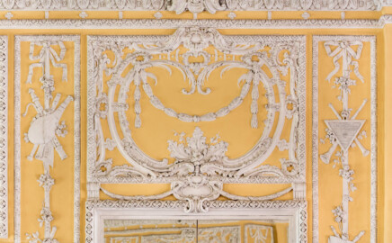 Schloss Bruchsal - Kammerflügel - Von innen - Kammermusiksaal - Ostwand, links der Mitte, oben - Stuckdekorationen über dem linken Spiegel  (Saal ursprünglich gestaltet von Joachim Günther; heute genutzt von den Bruchsaler Schlosskonzerten) (aufgenommen im Juli 2019, um die Mittagszeit)