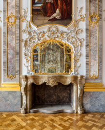 Schloss Bruchsal - Hauptbau / Corps de Logis - Beletage - Fürstensaal - Südseite, Mitte - Blick auf die Mitte der Südwand mit den Pilastern, dem Kamin, dem Spiegel, dem reichen Rocaille-Schmuck und dem unteren Teil des Portraits von Franz Christoph von Hutten zum Stolzenberg (aufgenommen im Juli 2019, am späten Vormittag)