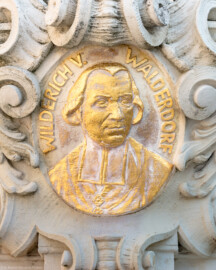 Schloss Bruchsal - Ehrenhof - Nördliches Tor, westlicher Torpfosten, Südseite - Wappenportrait von Philipp Franz Wilderich Nepomuk von Walderdorf (aufgenommen im Juli 2019, am späten Vormittag) Schloss Bruchsal - Ehrenhof - Nördliches Tor, westlicher Torpfosten, Südseite - Wappenportrait von Philipp Franz Wilderich Nepomuk von Walderdorf (aufgenommen im Juli 2019, am späten Vormittag)