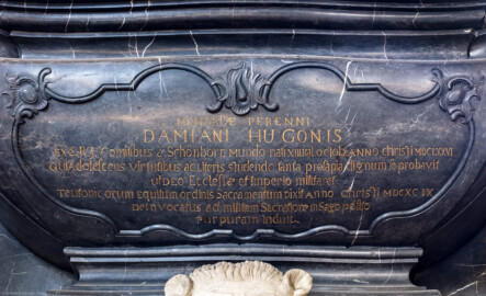 Bruchsal - Peterskirche / St. Peter - Westlicher Chorraum - Doppelgrabdenkmal für Damian Hugo Philipp von Schönborn-Buchheim und für August von Limburg-Stirum -  Von Innen / Von Nordost - Blick auf die Tumba für Damian Hugo Philipp von Schönborn-Buchheim und deren Inschrift im oberen Teil des Grabdenkmal; die Inschrift lautet auf Deutsch: "Dem ewigen Andenken des Damian Hugo aus dem Geschlecht der Grafen des Heiligen Römischen Reiches von Schönborn – der Welt geboren am 13. Tag, vor dem 1. Oktober im Jahr Christi 1667 -, der sich in seiner Jugend durch seine Tugenden und das Studium der Wissenschaften des bedeutenden Geschlechtes würdig erwies, für Gott die Kirche und das Reich zu kämpfen. Den Eid des Deutschen Ritterordens leistete er im Jahre Christi 1699, danach zum heiligeren Dienst berufen, legte er den Kriegsrock ab und den Purpurmantel an." (Epitaph entworfen von Johann Seitz, gefertigt von Stephan Strahl) (aufgenommen im September 2019, um die Mittagszeit)