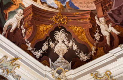 Schloss Bruchsal - Hauptbau / Corps de Logis - Beletage - Fürstensaal - Decke, äußere Zone, Nordwestecke - Ausschnitt aus der nordwestlichen äußeren Zone - Ausschnitt aus der Darstellung der Landwirtschaft, ein wichtiger Wirtschaftszweig Bruchsals - oben rechts: Anschnitt der Signatur von Wolfram Köberl mit dem Datum (1969) der Fertigstellung der Fresko-Rekonstruktion und dem Hinweis auf den originalen Maler (Johannes Zick) und das Datum (1751) der originalen Fertigstellung; unten: Scheinarchitektur mit zwei Putti (Deckenfresko urspünglich gemalt 1751 von Johannes Zick, originalgetreu rekonstruiert 1966 bis 1969 von Wolfram Köberl) (aufgenommen im Oktober 2019, am späten Vormittag)