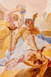 Schloss Bruchsal - Hauptbau / Corps de Logis - Beletage - Fürstensaal - Decke, Mitte, Zentrum nach Westen hin - Ausschnitt aus der westlichen mittleren inneren Zone - Mitte: Darstellung des Götterboten Hermes (mit Flügeln an Helm und Füßen), in der Hand den Hermesstab (ein Stab  mit zwei Flügeln, umschlungen von zwei Schlangen); links: ein Genius, eine Mitra (als Symbol für die geistliche Würde) über Hermes haltend; unten: Darstelllung des besiegten Ungeheuers Argos, dessen 100 Augen auf einem Tuch abgebildet sind (Deckenfresko urspünglich gemalt 1751 von Johannes Zick, originalgetreu rekonstruiert 1966 bis 1969 von Wolfram Köberl) (aufgenommen im Oktober 2019, am Nachmittag)