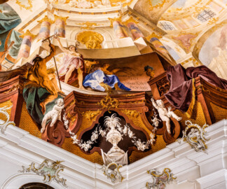Schloss Bruchsal - Hauptbau / Corps de Logis - Beletage - Fürstensaal - Decke, untere Zone, Nordwestecke - Ausschnitt aus der nordwestlichen äußeren Zone - Darstellung der Landwirtschaft, ein wichtiger Wirtschaftszweig Bruchsals - Links der Mitte (Frau mit Ähre): Darstellung der griechischen / römischen Fruchtbarkeitsgöttin Demeter / Ceres; links (Mann mit Rechen): Darstellung des Hirtengotts Pan, auch die Fruchtbarkeit symbolisierend; rechts der Mitte: Signatur von Wolfram Köberl mit dem Datum (1969) der Fertigstellung der Fresko-Rekonstruktion und dem Hinweis auf den originalen Maler (Johannes Zick) und das Datum (1751) der originalen Fertigstellung  (Deckenfresko urspünglich gemalt 1751 von Johannes Zick, originalgetreu rekonstruiert 1966 bis 1969 von Wolfram Köberl) (aufgenommen im Dezember 2019, um die Mittagszeit)