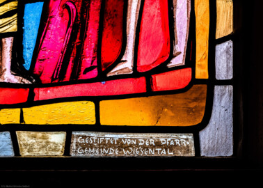 Waghäusel - Wallfahrtskirche - Von innen - Alter Chor - Nordwand  - Mittleres Fenster - Von Süden - Fenster "Die Passion" - Ausschnitt mit Stiftungshinweis (rechte Bahn, unterstes Feld) aus dem mittleren Chorfenster (Entwurf von Valentin Peter Feuerstein, Neckarsteinach, 1960; Ausführung von der Glaswerkstatt Meysen, Heidelberg) (aufgenommen im Februar 2020, am Nachmittag)
