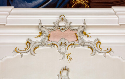 Schloss Bruchsal - Hauptbau / Corps de Logis - Beletage - Fürstensaal - Westwand, Mitte, oben - Blick auf eine Rocaille-Verzierung unterhalb des Deckenfreskos (aufgenommen im März 2020, am frühen Nachmittag)