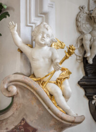 Bruchsal - Peterskirche / St. Peter - Westliches Querschiff, Südwand - Nepomukaltar - Von Nordwest - Blick auf den rechten unteren Putto des Nepomukaltars (Johannes von Nepomuk, 1350-1393, böhmischer Priester und Märtyrer, Brückenheiliger und Patron des Beichtgeheimnisses) (aufgenommen im April 2020, am frühen Nachmittag)