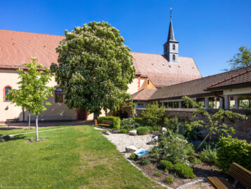 Waghäusel - Wallfahrtskirche - Von Süden - Blick auf den Garten, die Kirche und den Kirchturm sowie die Edith-Stein-Halle (rechts) (aufgenommen im April 2020, um die Mittagszeit)