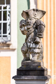 Schloss Bruchsal - Südliche Orangerie / Kavaliersbau, Westseite - Von Südwesten - Zwerg auf der Balustrade (links/nördlich der Mitte) (gehauen von Joachim Günther) (aufgenommen im Mai 2020, am Nachmittag)