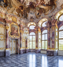 Schloss Bruchsal - Hauptbau / Corps de Logis - Beletage - Marmorsaal / Kaisersaal - Von Nordost - Blick nach Südwest in den Marmorsaal, auf die südliche (links) und westliche (rechts) Wand, die Stuckaturen, die Fenster, die Tür zum Gelben Zimmer (links) und zum Altan (rechts), die Supraporte "Die Befreiung des Prometheus" und auf das Deckenfresko (Deckenfresko und Supraporte urspünglich gemalt 1754 von Johannes Zick, originalgetreu rekonstruiert 1971 bis 1974 von Wolfram Köberl; Stuck urspünglich von Johann Michael Feuchtmayer dem Jüngeren, rekonstruiert 1962 bis 1969 von Jakob und Josef Schnitzer) (aufgenommen im Juli 2020, am späten Vormittag)