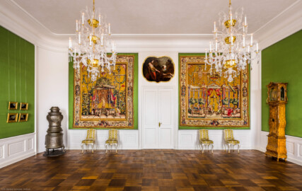 Schloss Bruchsal - Hauptbau / Corps de Logis - Von innen - Beletage - Jagdzimmer - Ostwand - Blick von Westen in das Jagdzimmer, links die vier Jagdgemälde von Anton Enzinger sowie der Kanonenofen, rechts eine Standuhr, in der Mitte die Tapisserien aus der Groteskenserie (aufgenommen im Oktober 2020, um die Mittagszeit)
