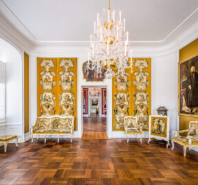 Schloss Bruchsal - Hauptbau / Corps de Logis - Beletage - Musikzimmer - Von Westen - Blick nach Osten in das Musikzimmer und auf die Enfilade vom Musikzimmer bis zum Schlafzimmer; an der Wand Savonnerien mit chinoisen Motiven, ebenso an den Möbeln; oben die Supraporte "Mucius Scaevola vor Porsenna" (gemalt von Johannes Zick), rechts ein Porträt von Franz Christoph von Hutten zum Stolzenberg (Maler unbekannt) (aufgenommen im Oktober 2020, am Nachmittag)
