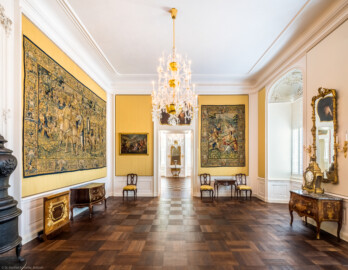 Schloss Bruchsal - Hauptbau / Corps de Logis - Von innen - Beletage - Gelbes Zimmer - Von Norden - Blick nach Süden in das Gelbe Zimmer und das Rote Zimmer; zu sehen sind die Tapisserien mit Szenen aus dem Alten Testament, hergestellt von Martin II Reymbouts, die Kommoden und der Spieltisch, gefertigt von Abraham Roentgen, sowie das Gemälde von Januarius Zick (aufgenommen im  November 2020, am späten Vormittag)