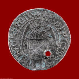 Städtisches Museum Bruchsal - Schloss Bruchsal - Hauptbau / Corps de Logis - Münzsammlung - Avers (Vorderseite) der Münze "Silberner Engelsgroschen" (dünn, Durchmesser 28 mm, mit Loch; Avers: Halbfigur eines Engels, Wappenschild mit zwei gekreuzten Schwertern, umlaufender Schriftzug FRIDERICUS JOHANNES GEORGIUS (verweist auf Kurfürst Friedrich III., Herzog Johann der Beständige und Herzog Georg der Bärtige); Revers: großes dreiteiliges Wappenschild (Allianzwappen der drei Herzöge), umlaufender Schriftzug GROSSVS NOVVS DVCVM SAXONIE (neuer Groschen der Herzöge von Sachsen); geprägt 1512 in Annaberg / Sachsen von Albrecht von Schreibersdorf; Fundort/-zeit: Bruchsal, Kaiserstraße, wohl 1948; Informationen recherchiert durch Doris Buhlinger M.A.); (aufgenommen im April 2021, am Nachmittag) Städtisches Museum Bruchsal - Schloss Bruchsal - Hauptbau / Corps de Logis - Münzsammlung - Avers (Vorderseite) der Münze "Silberner Engelsgroschen" (dünn, Durchmesser 28 mm, mit Loch; Avers: Halbfigur eines Engels, Wappenschild mit zwei gekreuzten Schwertern, umlaufender Schriftzug FRIDERICUS JOHANNES GEORGIUS (verweist auf Kurfürst Friedrich III., Herzog Johann der Beständige und Herzog Georg der Bärtige); Revers: großes dreiteiliges Wappenschild (Allianzwappen der drei Herzöge), umlaufender Schriftzug GROSSVS NOVVS DVCVM SAXONIE (neuer Groschen der Herzöge von Sachsen); geprägt 1512 in Annaberg / Sachsen von Albrecht von Schreibersdorf; Fundort/-zeit: Bruchsal, Kaiserstraße, wohl 1948; Informationen recherchiert durch Doris Buhlinger M.A.); (aufgenommen im April 2021, am Nachmittag)