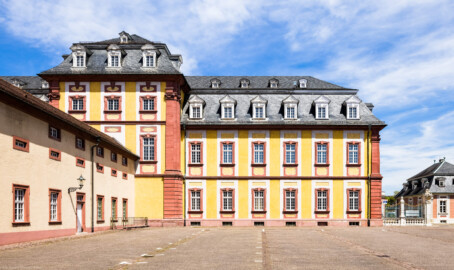 Schloss Bruchsal - Kirchenflügel / Hofkirche - Von außen - Von Süden - Blick vom Seminarbau / der Pagerie auf die Südostseite des Kirchenflügels und den Mittelrisalit, links der "Finstere Gang" (Verbindungsgang zwischen Hofkirche und Kirchturm), rechts das Hofzahlamt / das Schlosscafé (aufgenommen im Mai 2021, am frühen Nachmittag)
