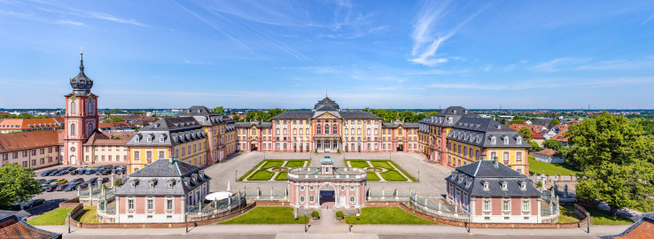 Schloss Bruchsal - Zentrum der Schlossanlage - Von Außen - Von Osten - Blick von der Plattform des Kanzleibaus nach unten auf die Dreiflügelanlage; in der Mitte der Hauptbau / das Corps de Logis, links der Mitte der südliche Verbindungsbau, links davon der Kirchenflügel / die Hofkirche / St. Damian und Hugo, links davon der Kirchturm, rechts der Mitte der nördliche Verbindungsbau, rechts davon der Kammerflügel / das Amtsgericht; vorne links das Hofzahlamt (heute Schlosscafé), vorne in der Mitte das Torwachtgebäude, vorne rechts das Hofkontrollamt; in der Mitte der Anlage der Ehrenhof (aufgenommen im Juni 2021, am späten Vormittag) Schloss Bruchsal - Zentrum der Schlossanlage - Von Außen - Von Osten - Blick von der Plattform des Kanzleibaus nach unten auf die Dreiflügelanlage; in der Mitte der Hauptbau / das Corps de Logis, links der Mitte der südliche Verbindungsbau, links davon der Kirchenflügel / die Hofkirche / St. Damian und Hugo, links davon der Kirchturm, rechts der Mitte der nördliche Verbindungsbau, rechts davon der Kammerflügel / das Amtsgericht; vorne links das Hofzahlamt (heute Schlosscafé), vorne in der Mitte das Torwachtgebäude, vorne rechts das Hofkontrollamt; in der Mitte der Anlage der Ehrenhof (aufgenommen im Juni 2021, am späten Vormittag)