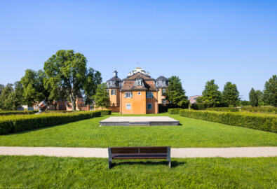 Waghäusel - Eremitage - Von Außen - Von Nordost - Blick nach Südwesten auf das Gesamt-Ensemble: in der Mitte der nordöstliche Kavalierspavillon (der "Gardebau"), dahinter der Zentralbau mit den Flügelanbauten, links hinter den Bäumen der südöstliche Kavalierspavillon (der "Küchenbau") (aufgenommen im Juli 2021, am Vormittag)