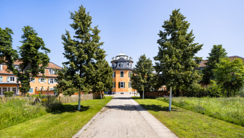 Waghäusel - Eremitage - Von Außen - Von Südwest - Blick vom südwestlichen Wegzugang auf den Hauptbau und die Südfassade eines Flügelanbaus, links der südwestliche Kavalierspavillon (der "Fremdenbau"), davor der "Hochzeitsgarten", rechts hinter den Bäumen der südöstliche Kavalierspavillon (der "Küchenbau") (aufgenommen im Juli 2021, am späten Vormittag)